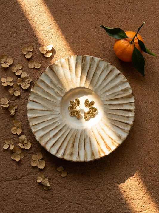 Decorative ceramic plate with floral design on a brown surface with flowers and an orange.